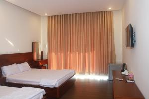 um quarto de hotel com duas camas e uma televisão em My Ca Hotel em Cam Ranh
