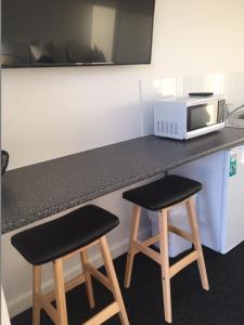 a kitchen with two stools and a microwave on a counter at Port Lincoln Shark Apartment 1 in Port Lincoln