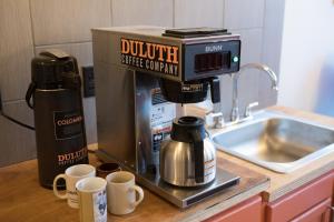 a coffee machine sitting on a counter next to cups at Hostel du Nord in Duluth