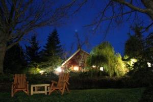 duas cadeiras sentadas em frente a uma casa à noite em Pretty River Valley Country Inn em Nottawa