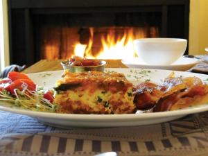 un plato de comida en una mesa frente a una chimenea en Pretty River Valley Country Inn, en Nottawa
