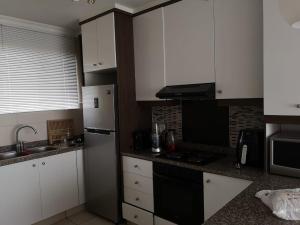 a kitchen with white cabinets and a black refrigerator at 84 Camarque Umdloti beach in Umdloti