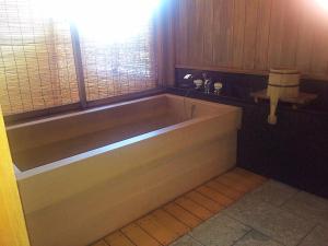 uma banheira na casa de banho com uma janela em Ise Todaya Ryoan em Ise
