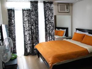 a bedroom with a bed with orange pillows and curtains at 4Q tower D Manhanttan Heights Cubao QC in Manila