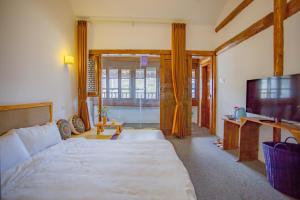 a bedroom with a large bed and a flat screen tv at Log Cabin in Dali