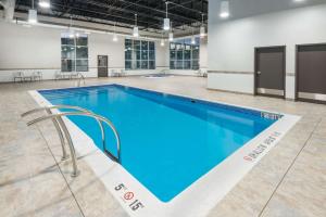 a large swimming pool with blue water in a building at Microtel Inn & Suites by Wyndham Sudbury in Sudbury