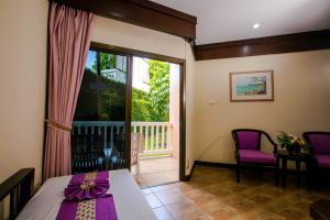 Habitación con cama y balcón con ventana. en Kata Poolside Resort SHA Extra Plus, en Kata Beach