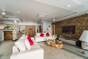 sala de estar con muebles blancos y pared de ladrillo en Fabuleuse villa Alizés vue mer, avec Staff et véhicule 4x4 en Ban Bang Po