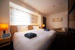 Un dormitorio con una gran cama blanca y una ventana en Hotel Forza Nagasaki en Nagasaki