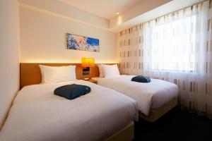 two beds in a hotel room with a window at Hotel Forza Nagasaki in Nagasaki +34 photos
