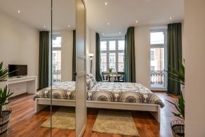 a bedroom with a king sized bed and windows at KATO Apartamenty Słowackiego in Katowice