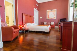 ヘレス・デ・ラ・フロンテーラにあるホテル パラシオ ガルベイの赤い壁のベッドルーム1室、ベッド1台、ソファが備わります。