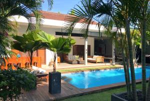 a swimming pool in a backyard with palm trees at Premium Villas Seminyak I in Seminyak