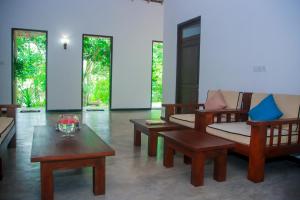 a living room with couches and tables and windows at Villa Greenary in Unawatuna