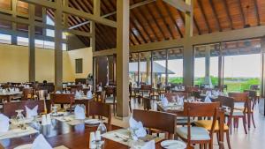 uma sala de jantar com mesas, cadeiras e janelas em Amora Lagoon Hotel em Katunayaka