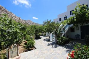 Una pasarela a través de un patio con flores y árboles en Akrogiali Apartments, en Lefkos Karpathou