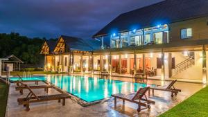a house with a swimming pool with benches in front of it at Amora Lagoon Hotel in Katunayaka