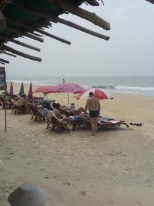 a group of people sitting on the beach under umbrellas at Casberly Apartment in Varca