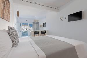 biała sypialnia z dużym łóżkiem i krzesłami w obiekcie Anatoli Luxury Studios & Suites w mieście Astypalea