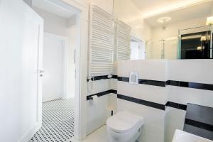 a bathroom with a white toilet and a black and white tile floor at Premier Apartment with Sauna by Grand Apartments in Sopot