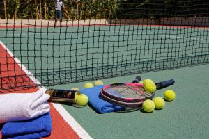 een persoon met een tennisracket en ballen op een tennisbaan bij Rethymno Mare & Water Park in Skaleta
