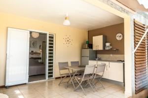 eine Küche und ein Esszimmer mit einem Tisch und Stühlen in der Unterkunft Fleur de canne in Sainte-Rose