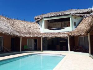 a villa with a swimming pool and a thatch roof at Antsanitia - Domaine du Mandravasarotra in Antsianitia