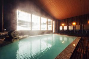 a large swimming pool in a room with a window at Meitoya So in Zaō Onsen