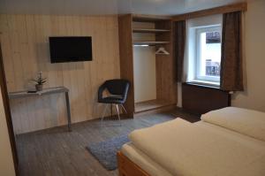 a bedroom with a bed and a chair and a television at Berghof in Berwang