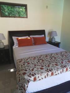 a bed with orange pillows in a bedroom at Coyaba Tropical Elegant Adult Guesthouse in Manuel Antonio