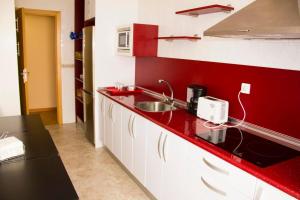 a red kitchen with a sink and a microwave at Gala II in Soria