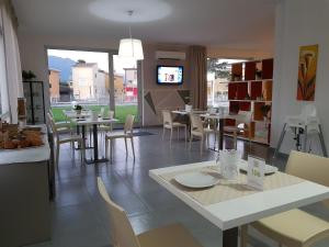 una sala da pranzo con tavoli, sedie e TV di Dodo House a Nocera Inferiore