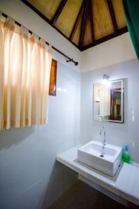Baño blanco con lavabo y espejo en Fantastic Cottages, en Gili Meno