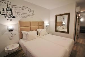 a hotel room with two beds and a mirror at Villa Ana Margarida Hotel in Ericeira