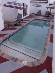 uma piscina com duas cadeiras e um guarda-sol em Fourties Guest House em Phalaborwa