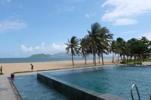a swimming pool next to a beach with palm trees at Moon house tropical garden - Lavender in Nha Trang