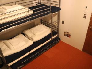two bunk beds in a room with a red floor at Guest House MARUYA in Atami