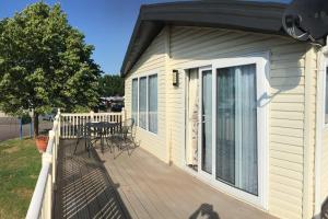 Casa con terraza con mesa y sillas en Mikanda Lodge en Clacton-on-Sea