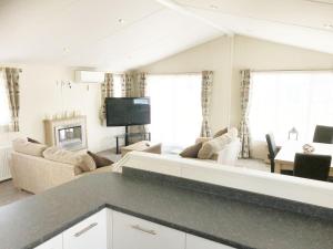 sala de estar con sofá y TV en Mikanda Lodge en Clacton-on-Sea
