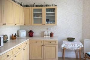 a kitchen with wooden cabinets and a counter top at Millbrook in Helston +17 photos