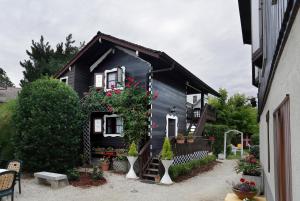 Una casa negra con flores a un lado. en HOTEL LES MARRONNIERS, en Thonon-les-Bains