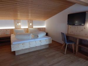 a bedroom with a bed and a desk and a television at Apart Renate - Silvretta Card Premium Betrieb in Galtür