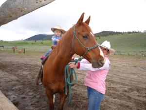 een vrouw die een kind op een paard vasthoudt bij Parade Rest Ranch in West Yellowstone