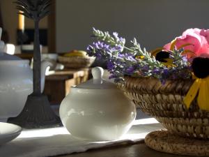 una mesa con un jarrón blanco y cestas de flores en Le Renard d'Introd en Introd