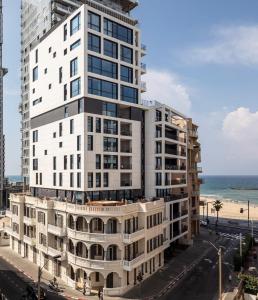 a tall white building next to a beach at Renoma Apartments in Tel Aviv