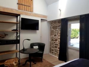 a bedroom with a bed and a table and a window at Le Colombier Bretagne in Louannec