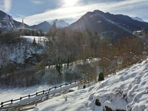 einen schneebedeckten Hügel mit einem Zaun und Bergen in der Unterkunft Il Rifugio della Volpe in Introd