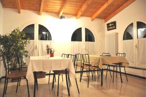 a dining room with two tables and chairs and windows at B&B Nelly G in Carbuta