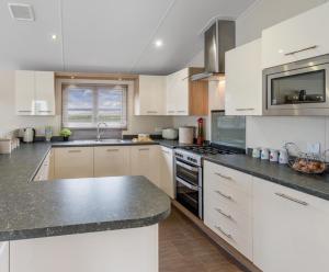 eine Küche mit weißen Schränken und einer schwarzen Arbeitsplatte in der Unterkunft Mikanda Lodge in Clacton-on-Sea