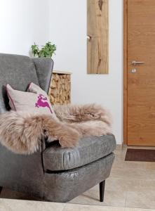 a grey couch with a brown fur pillow on it at Appartementhaus Mountain Room in Altenmarkt im Pongau